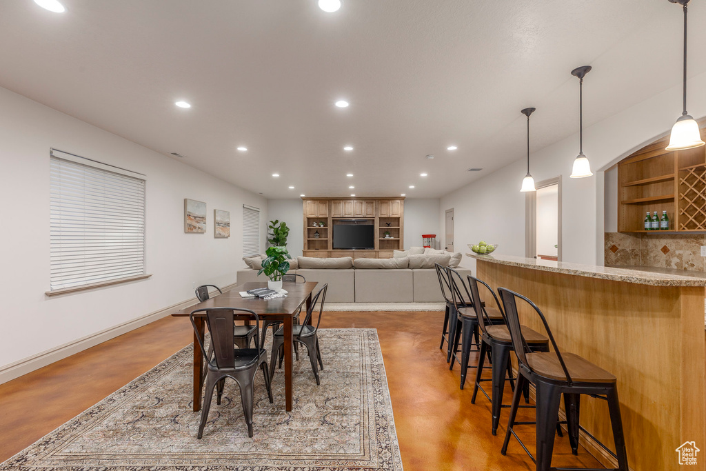 Dining space featuring concrete flooring, recessed lighting, and bar