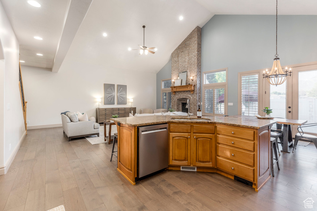 Kitchen with stainless steel dishwasher, a chandelier, open floor plan, dark wood-type flooring, and a brick fireplace