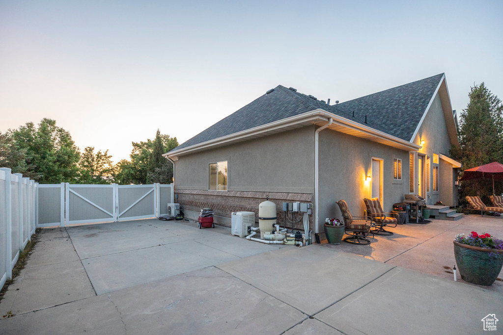 View of home\'s exterior featuring a gate, roof with shingles, a patio area, and stucco siding