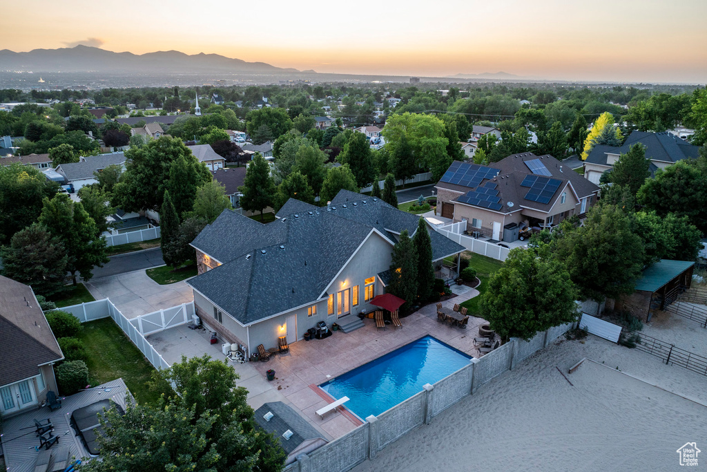Aerial view at dusk of view of pool area, a mountain view, and a residential view
