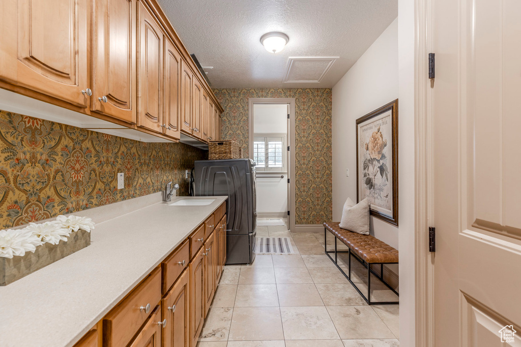 Laundry room featuring cabinet space, a textured ceiling, light tile patterned flooring, washer and dryer, and wallpapered walls