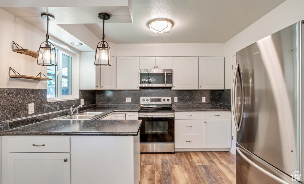 Kitchen featuring stainless steel appliances, dark countertops, and white cabinetry