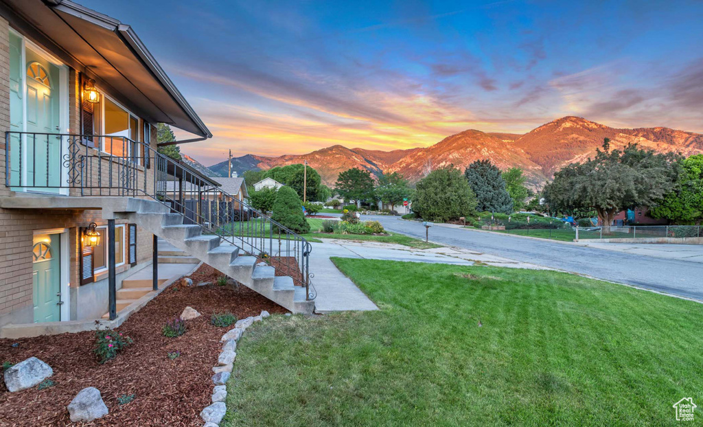 Yard at dusk with stairway, a mountain view, and a yard