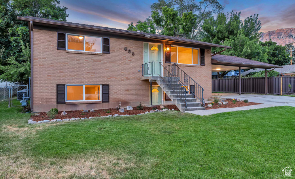 View of front of home featuring concrete driveway, brick siding, an attached carport, and stairs
