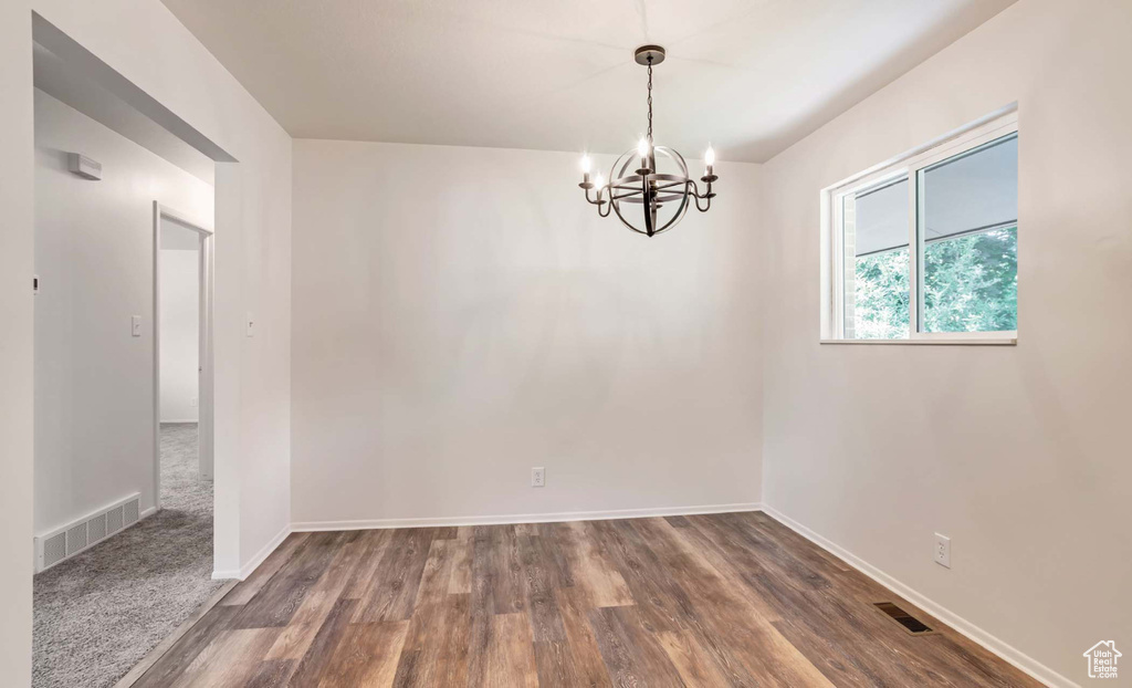 Empty room featuring a chandelier and wood finished floors