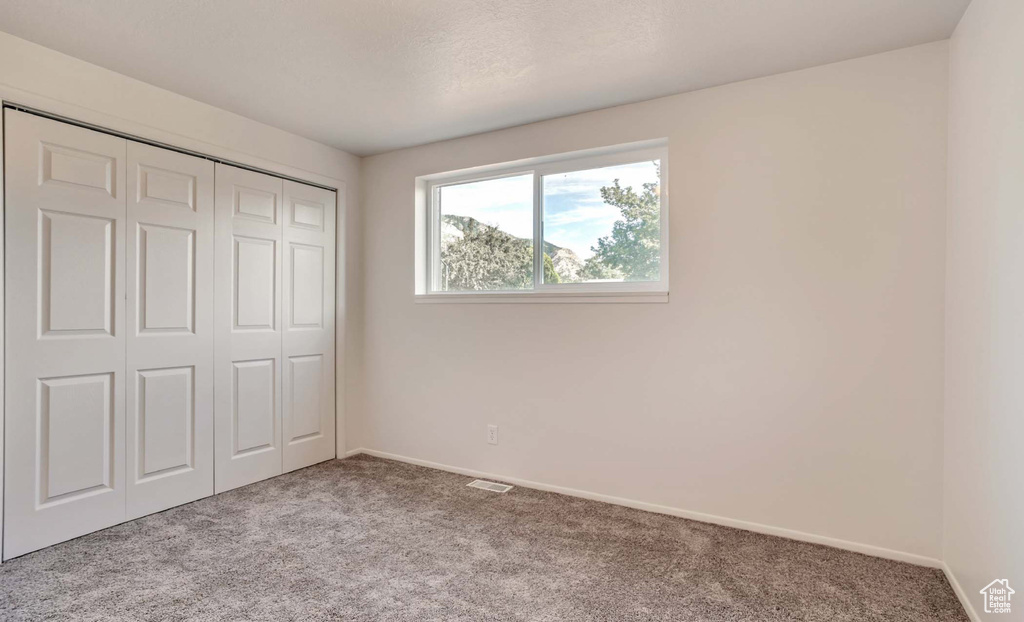 Unfurnished bedroom with carpet and a closet