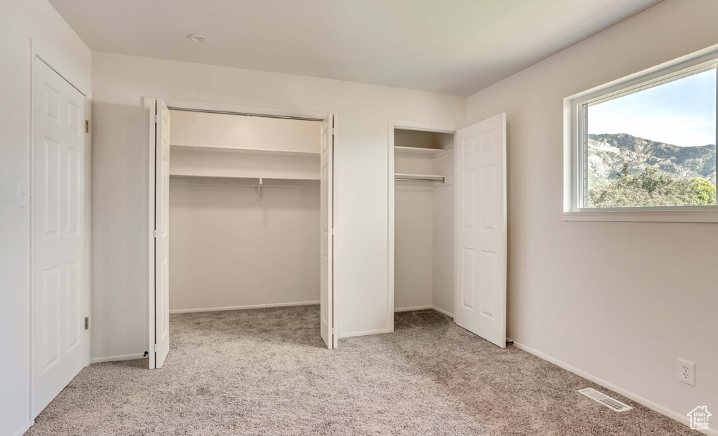 Unfurnished bedroom with carpet floors and two closets