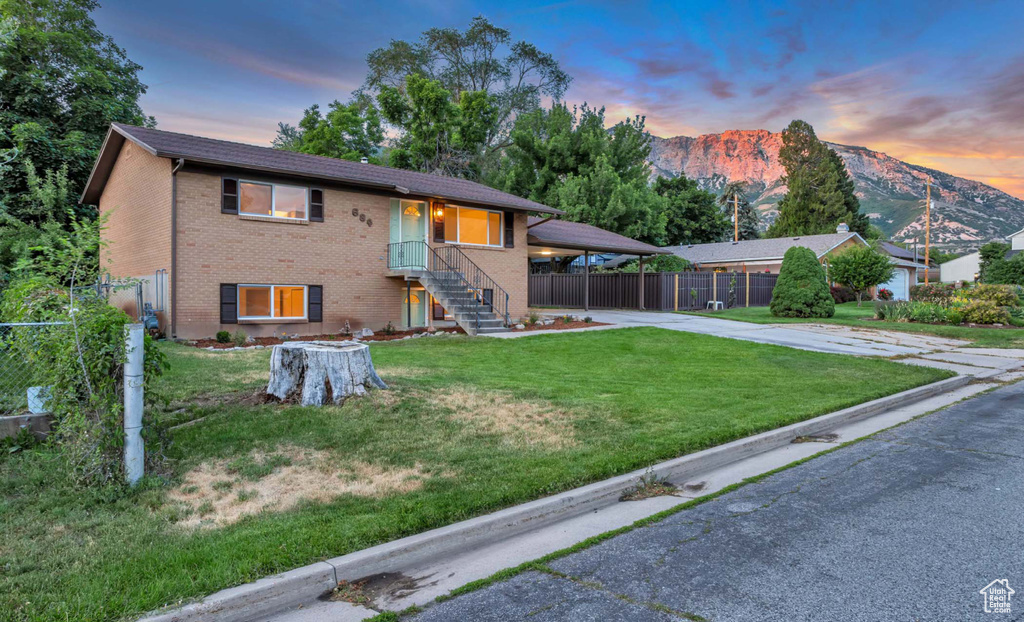 View of front of property with driveway, brick siding, a mountain view, and a carport