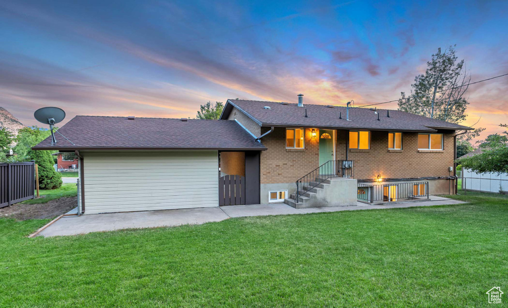 Back of house at dusk with brick siding, a patio, and a shingled roof