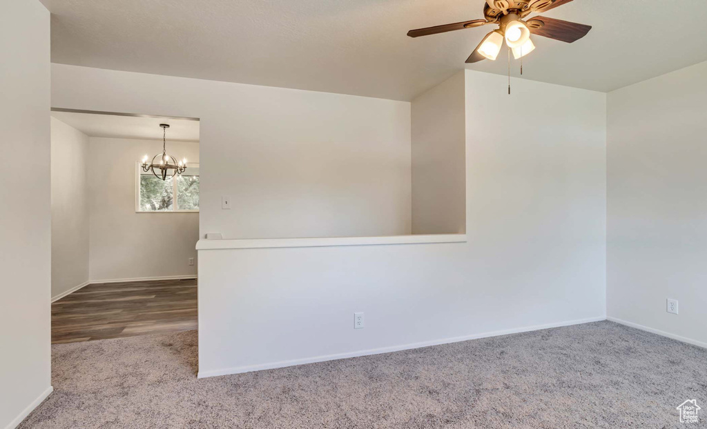 Carpeted spare room featuring ceiling fan and a chandelier