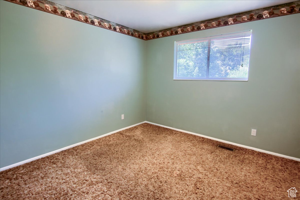 Carpeted spare room featuring baseboards