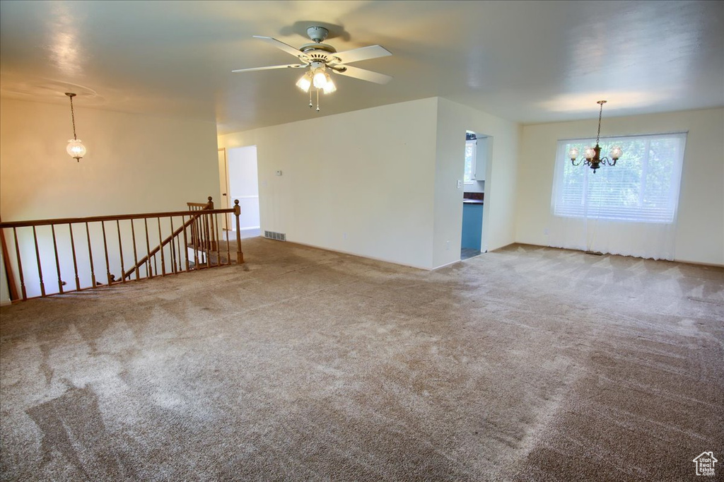 Empty room with carpet floors, a chandelier, and a ceiling fan