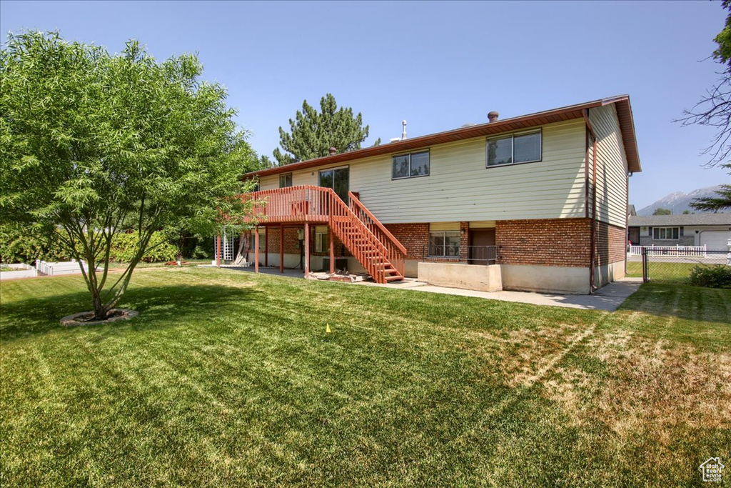 Rear view of house featuring stairs, a deck, and brick siding