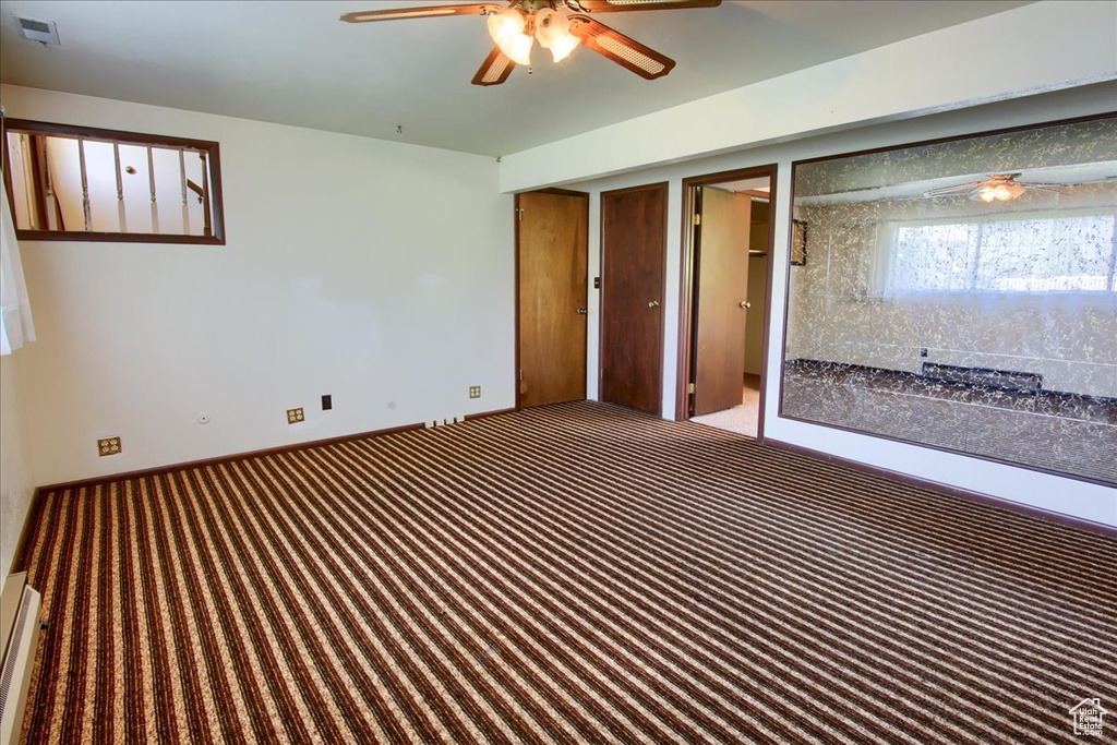 Carpeted empty room featuring ceiling fan and baseboards