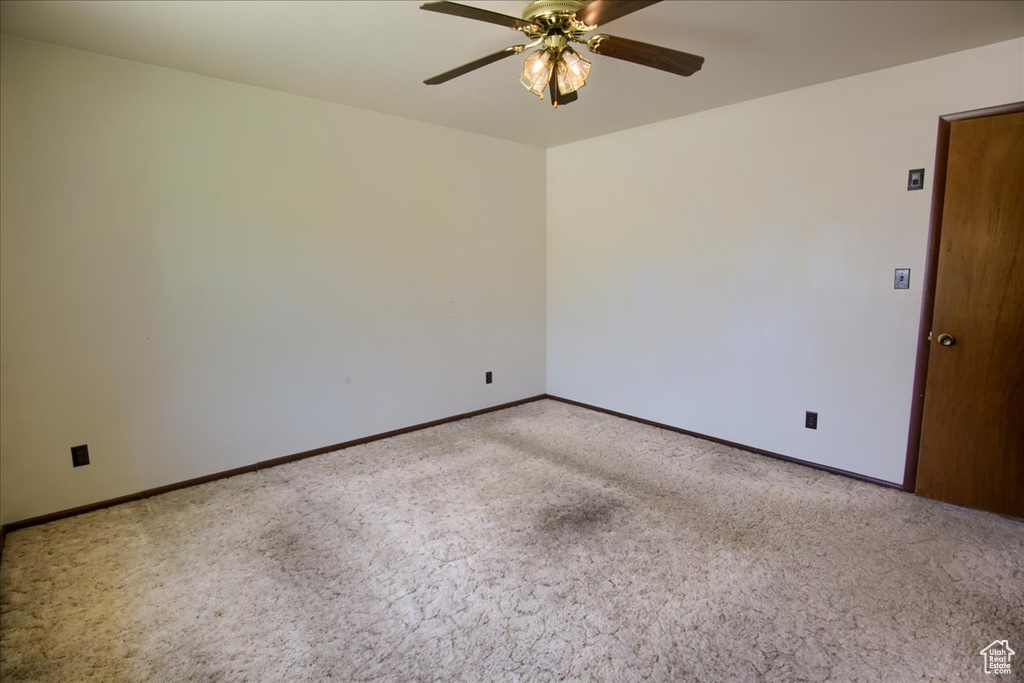 Carpeted empty room featuring ceiling fan and baseboards