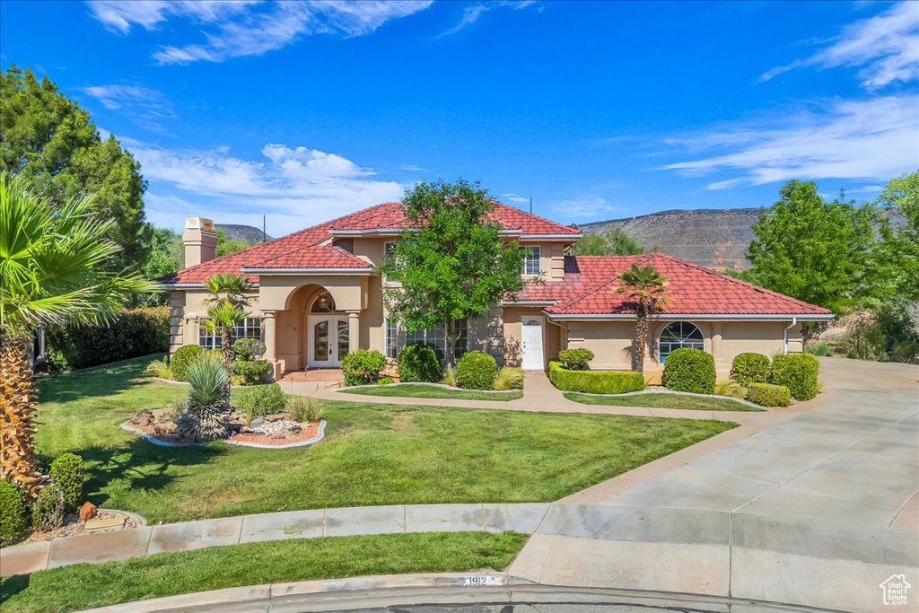 Mediterranean / spanish house featuring french doors, stucco siding, a chimney, and a tile roof