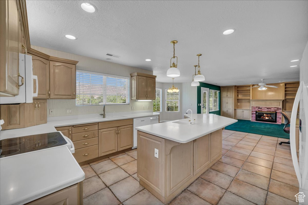 Kitchen with white appliances, light countertops, ceiling fan, an island with sink, and recessed lighting