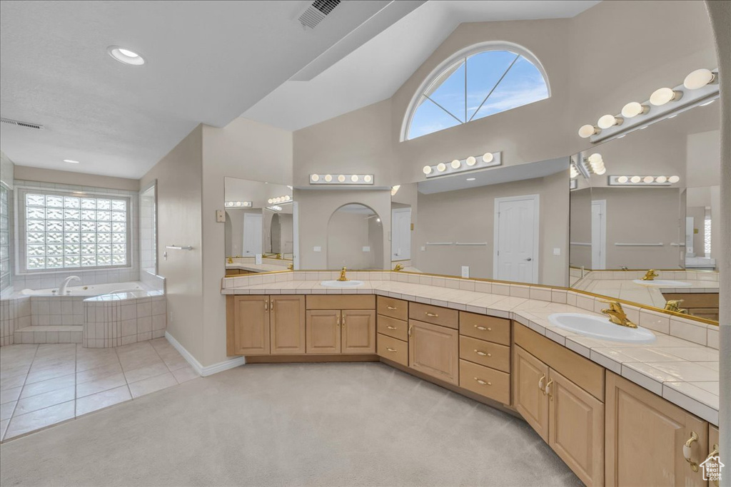 Full bath featuring double vanity, a garden tub, and high vaulted ceiling