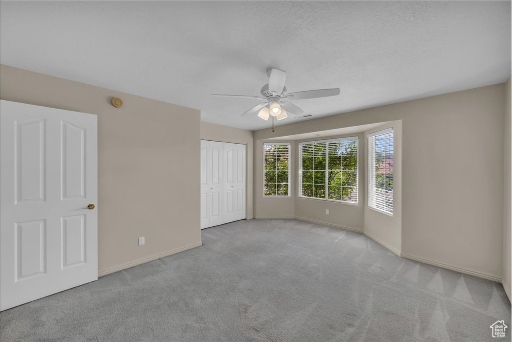 Unfurnished bedroom featuring carpet flooring, a closet, a ceiling fan, and a textured ceiling