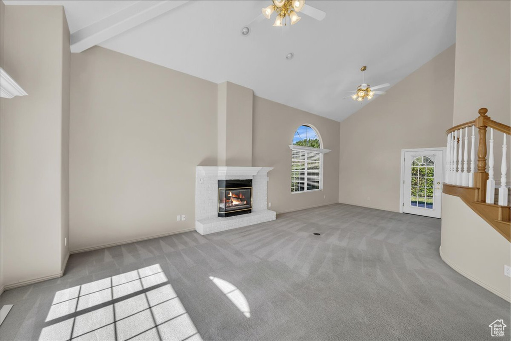 Unfurnished living room with high vaulted ceiling, ceiling fan, plenty of natural light, and carpet