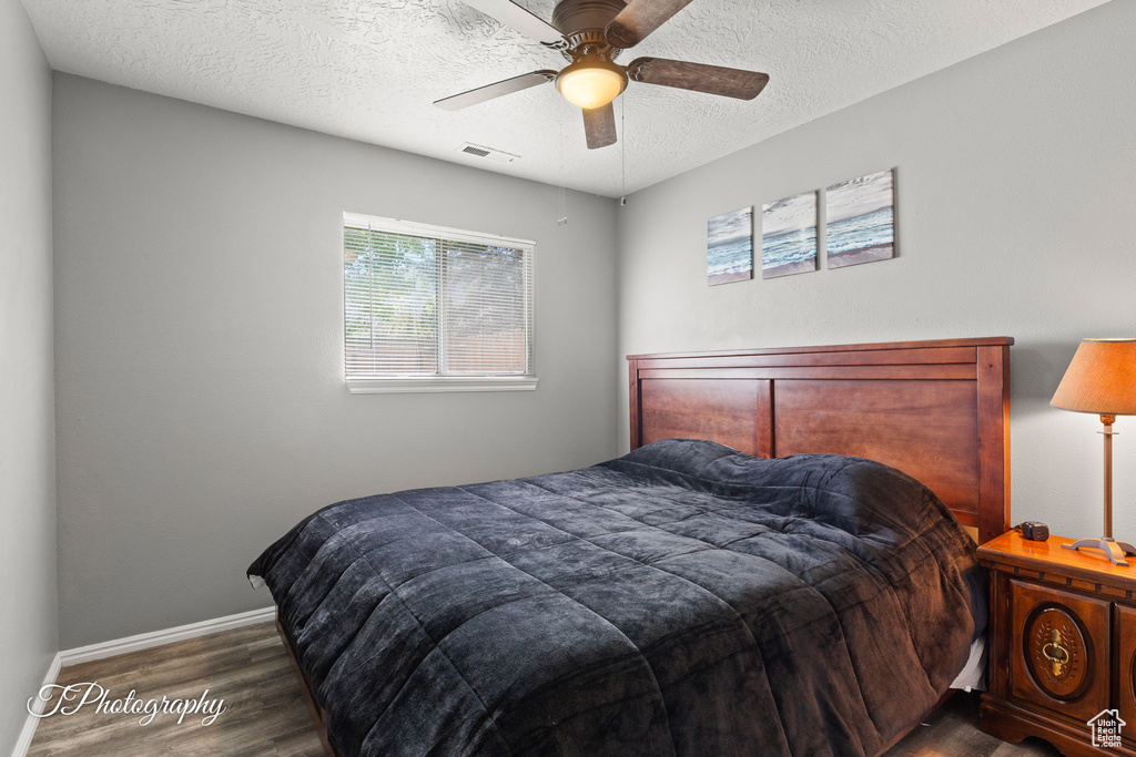 Bedroom with dark wood-style flooring, a textured ceiling, and ceiling fan