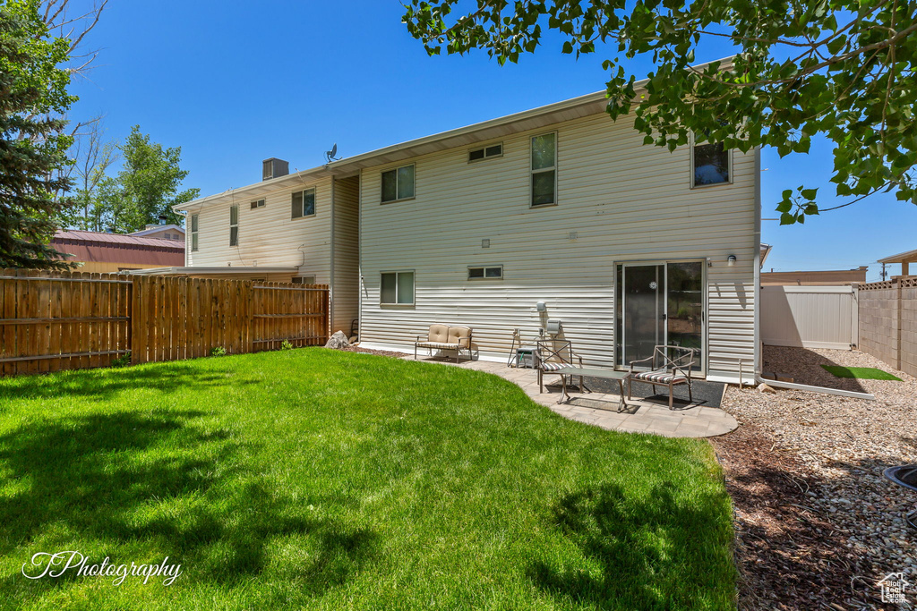 Rear view of house with a fenced backyard and a patio