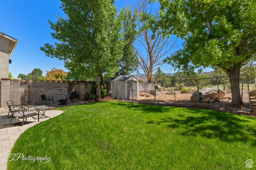 Fenced backyard featuring a shed and a patio area