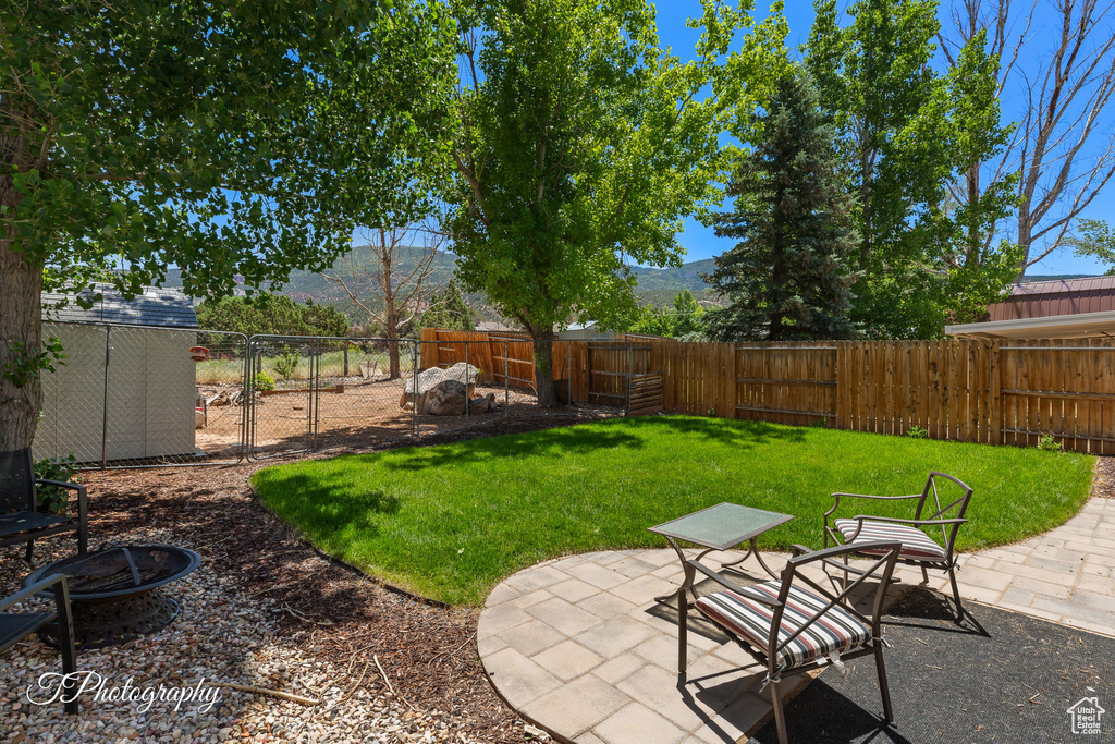 Fenced backyard with an outdoor fire pit, a patio, and a mountain view