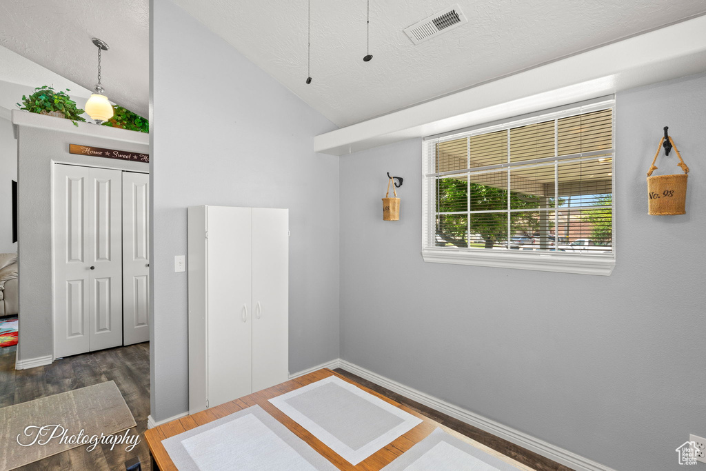 Spare room with wood finished floors, lofted ceiling, and a textured ceiling