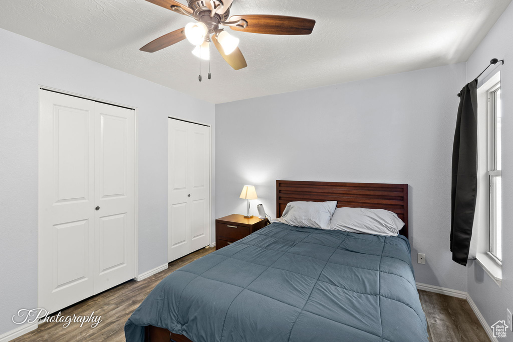 Bedroom with wood finished floors, two closets, and a ceiling fan