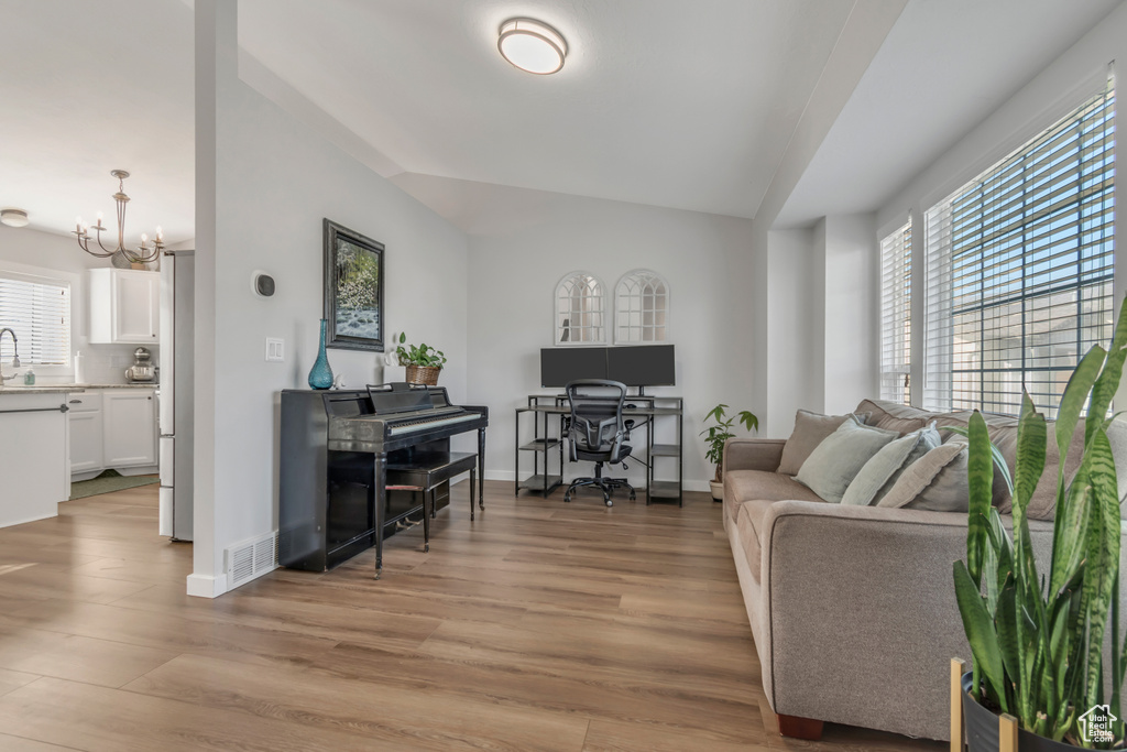 Living room featuring a chandelier, light wood finished floors, an office area, and vaulted ceiling