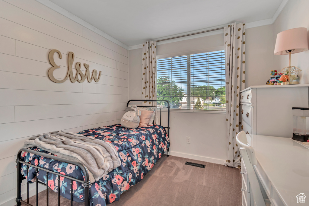 Carpeted bedroom with crown molding and wood walls