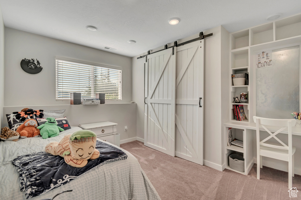 Bedroom featuring a barn door and light colored carpet