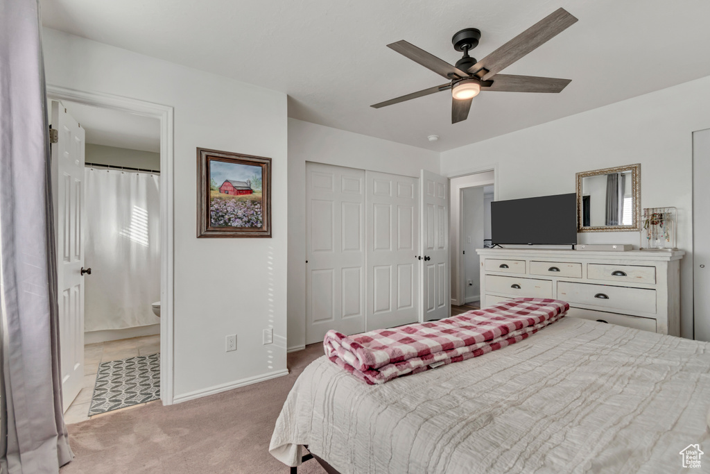 Bedroom with a closet, light colored carpet, connected bathroom, and a ceiling fan