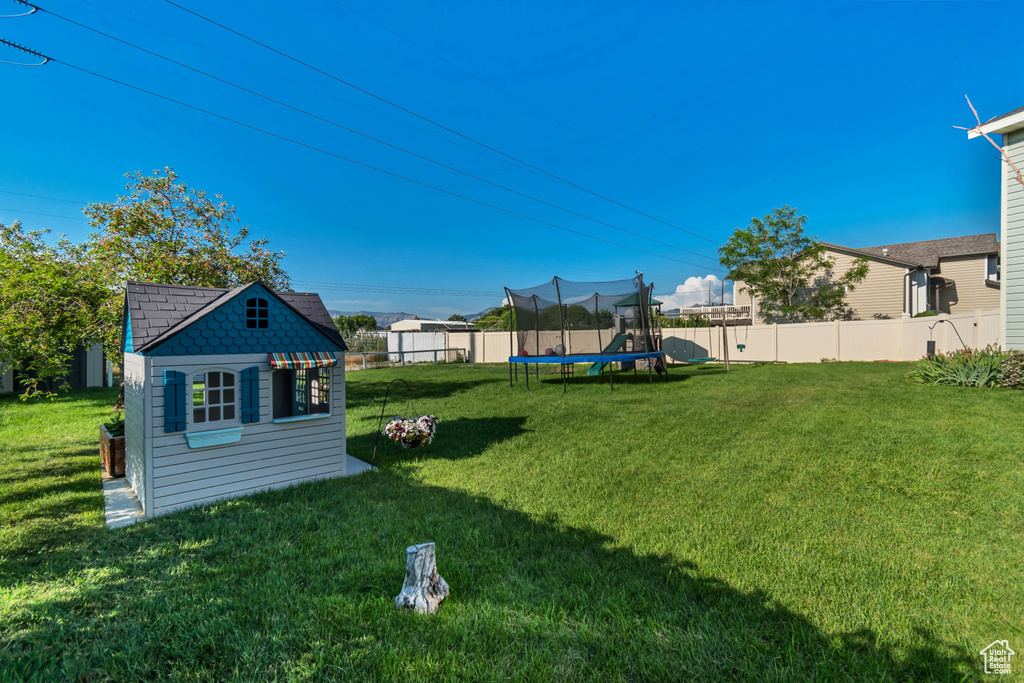 Fenced backyard with a trampoline and an outbuilding