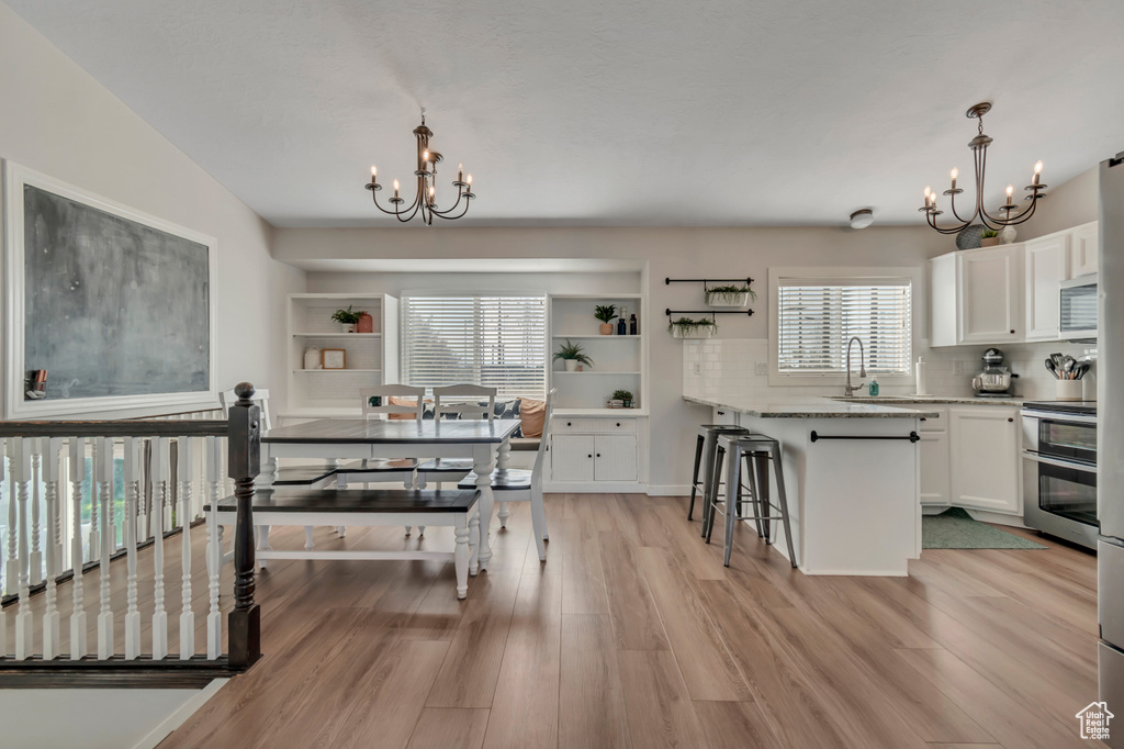Dining space with a chandelier, healthy amount of natural light, and light wood finished floors