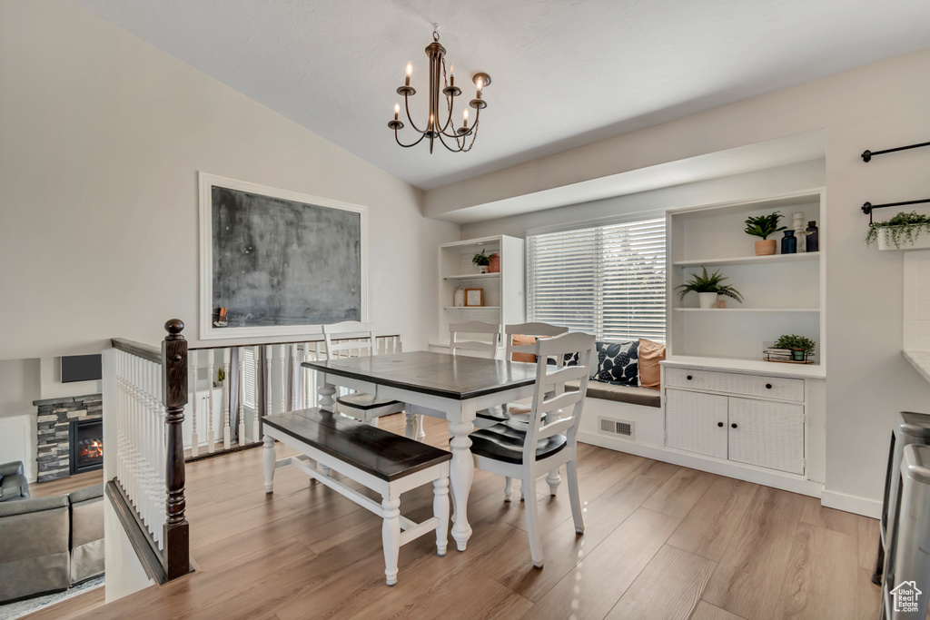 Dining space with a chandelier, light wood-type flooring, and vaulted ceiling
