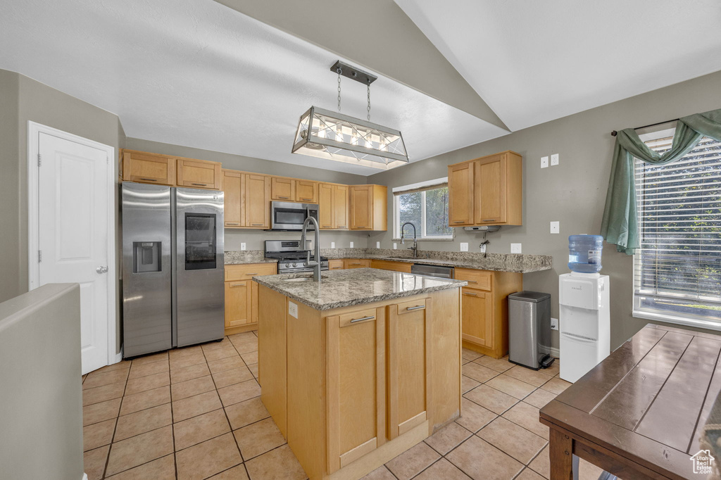 Kitchen featuring stainless steel appliances, lofted ceiling, light tile patterned floors, an island with sink, and light stone countertops