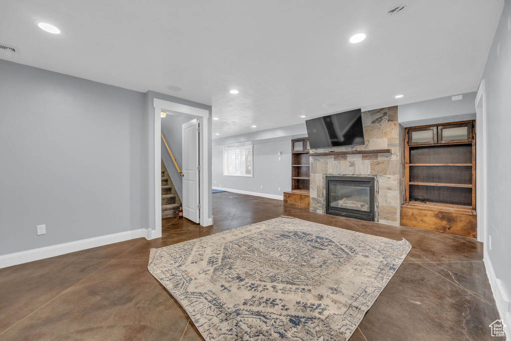 Living area featuring finished concrete flooring, stairway, a large fireplace, and recessed lighting
