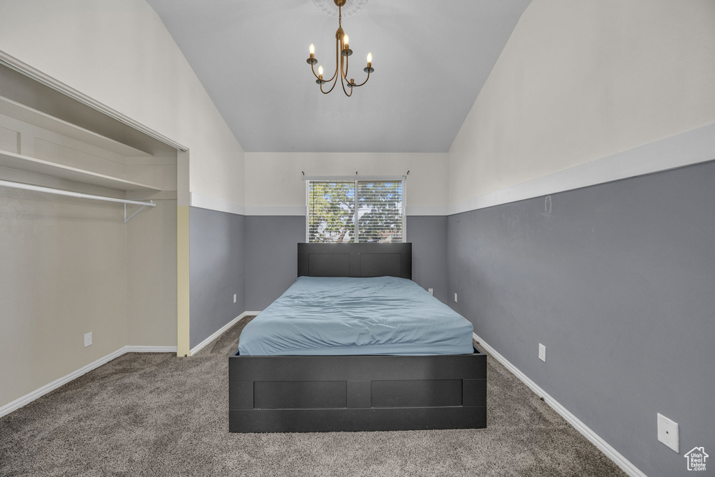 Carpeted bedroom featuring a chandelier and vaulted ceiling
