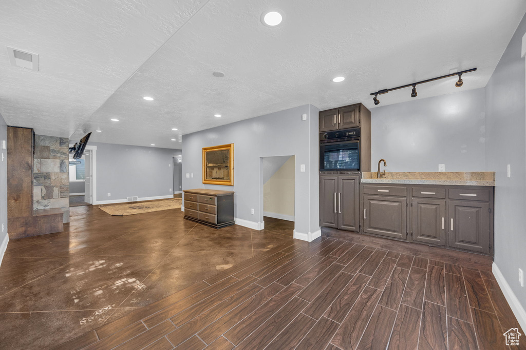 Unfurnished living room with dark wood-style flooring, track lighting, and recessed lighting