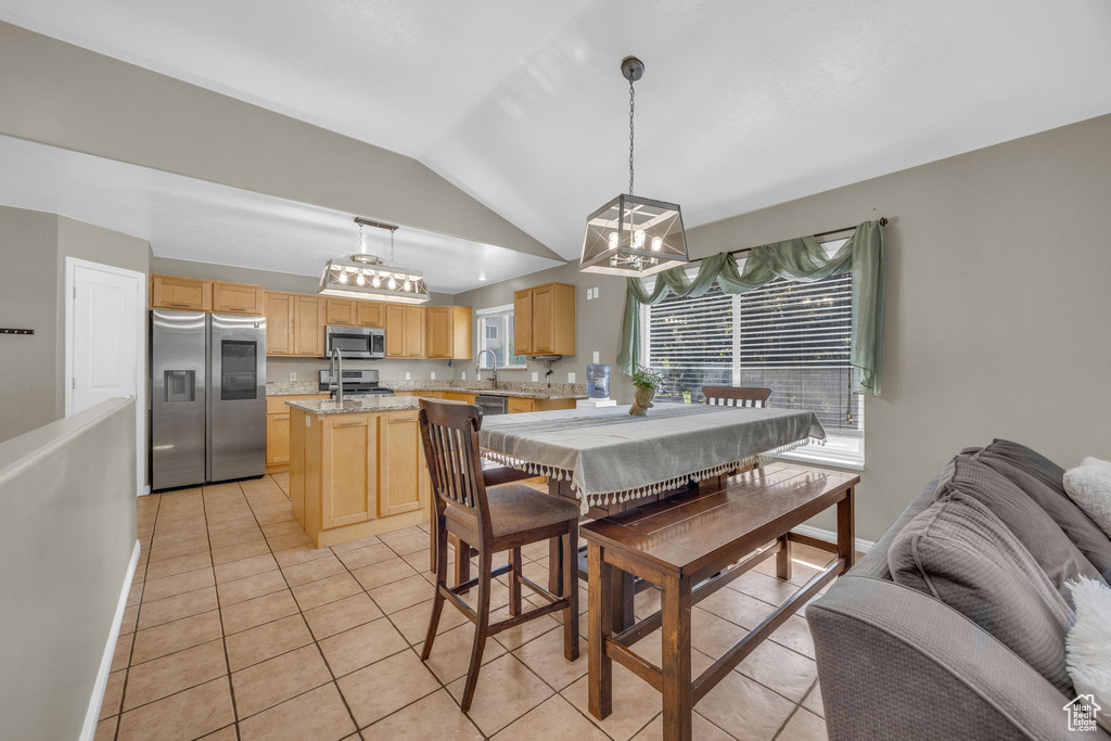 Dining area featuring vaulted ceiling, light tile patterned flooring, and a chandelier
