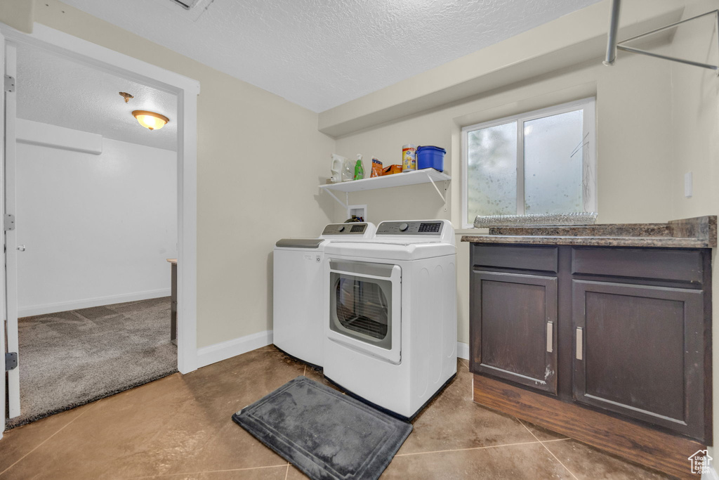Laundry room with separate washer and dryer and a textured ceiling