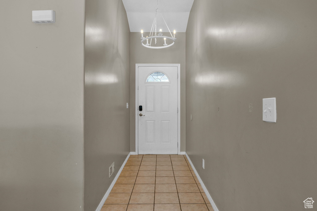 Doorway to outside featuring a chandelier and light tile patterned floors