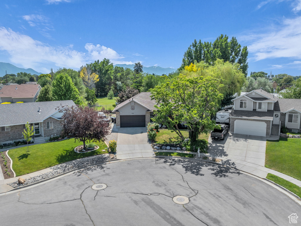 View of front facade featuring driveway, a front yard, a mountain view, and a residential view