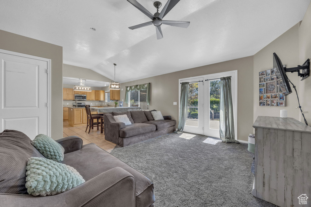 Living room featuring vaulted ceiling, ceiling fan, and light colored carpet