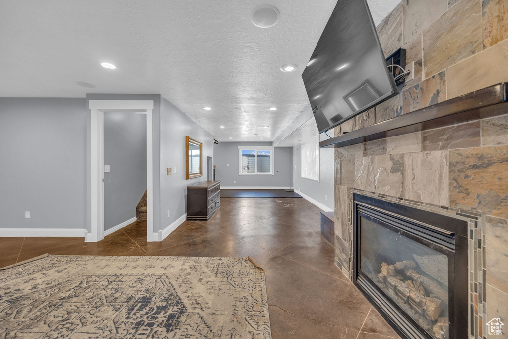 Unfurnished living room featuring a tiled fireplace, recessed lighting, stairs, and finished concrete flooring
