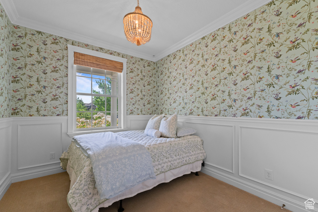 Bedroom with a chandelier, ornamental molding, wallpapered walls, wainscoting, and a decorative wall