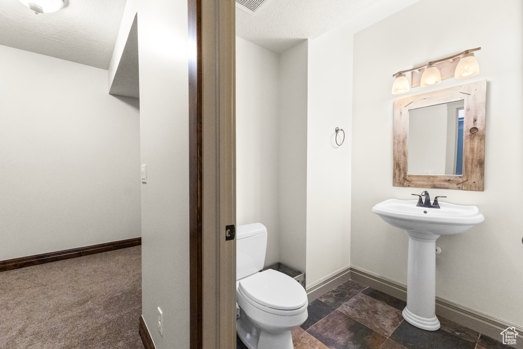 Half bathroom featuring a textured ceiling and stone finish flooring