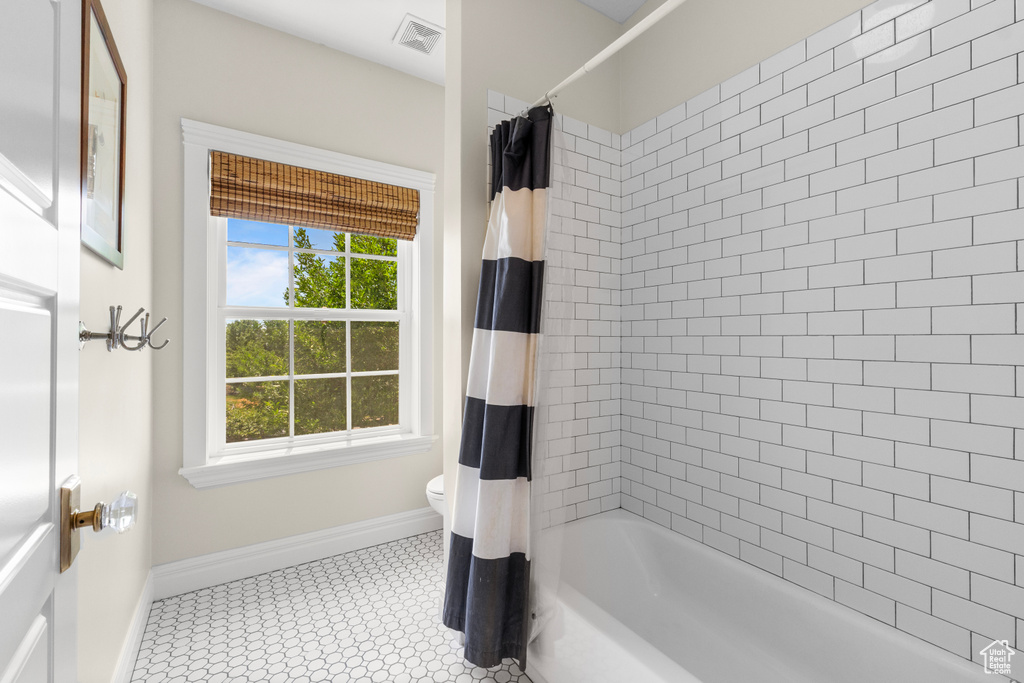 Full bath featuring baseboards and shower / bath combo with shower curtain